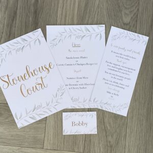 3 Leaflets And Nameplate With A Floral Design And Wording On This Laying On A Grey Floor